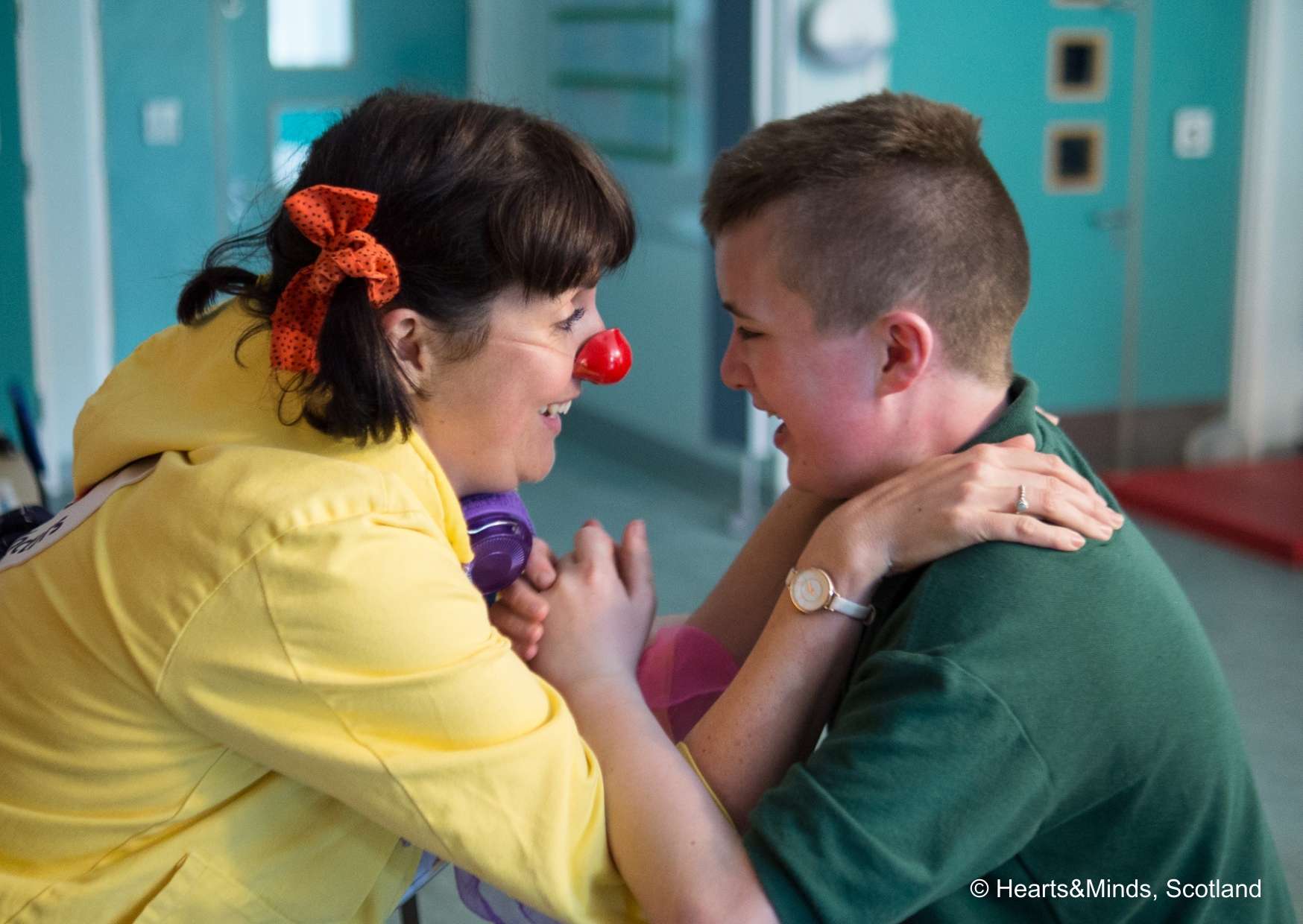 A female clown gives a happy boy a hug